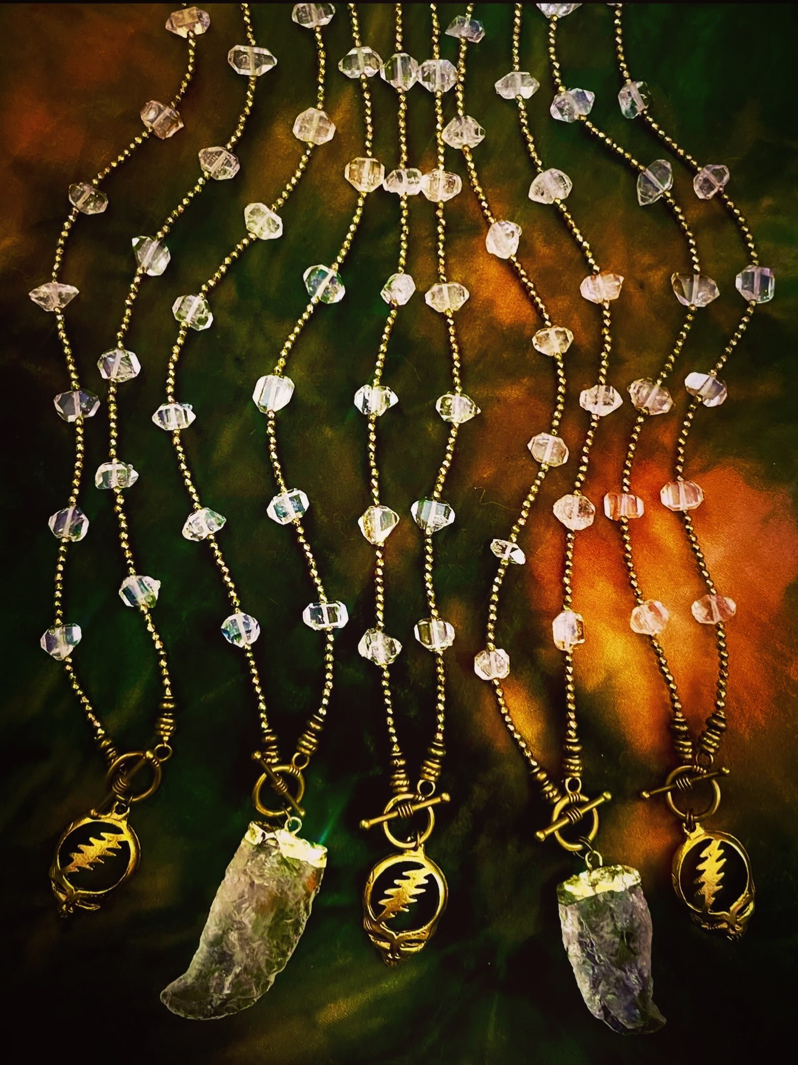 Herkimer diamond necklaces arranged on green and gold fabric